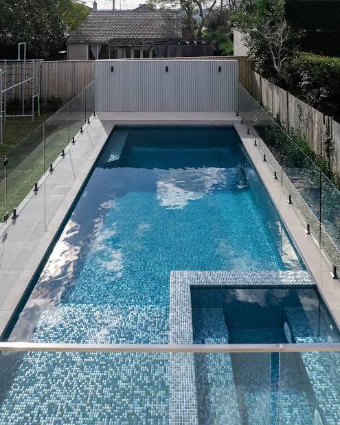 Swimming pool and spa surrounded by glass pool barriers