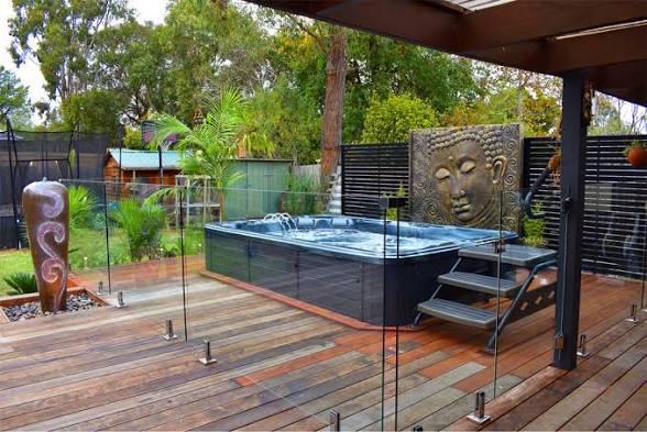 Outdoor spa enclosed by glass safety barriers